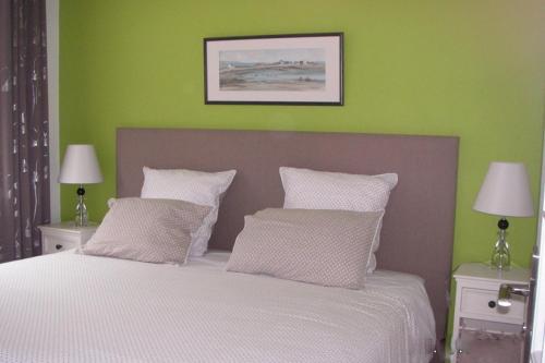 een slaapkamer met een wit bed en groene muren bij Les Coquelicots classé 3 étoiles in Paimpol