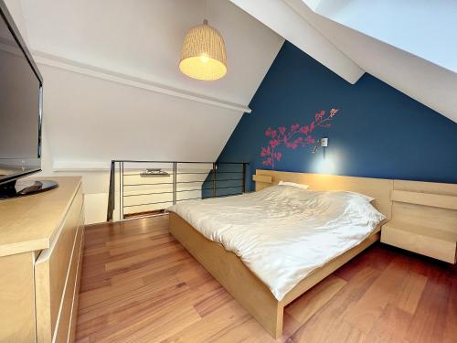 ein Schlafzimmer mit einem Bett und einer blauen Wand in der Unterkunft Suite duplex salon-bureau & chambre en mezzanine in Opprebais