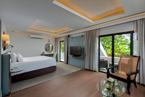 a bedroom with a bed and a desk and a tv at The Boathouse Phuket-SHA Plus in Kata Beach