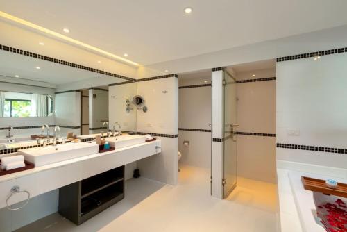a bathroom with two sinks and a large mirror at The Boathouse Phuket-SHA Plus in Kata Beach