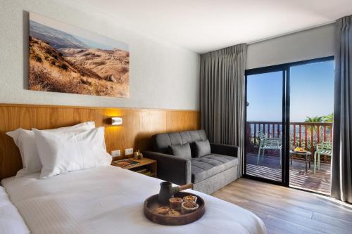 a hotel room with a bed and a couch and a balcony at Roxon Desert Arad in Arad