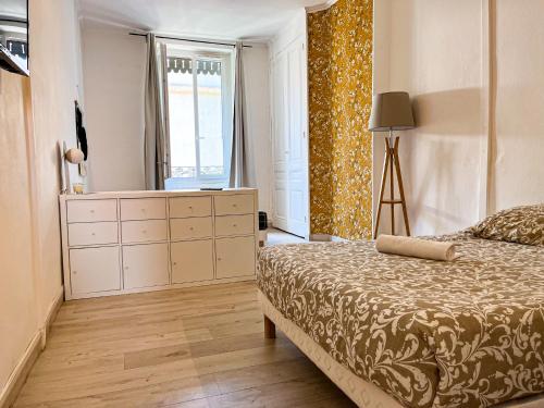 a bedroom with a bed and a dresser and a window at Suite Magelan in Villeurbanne