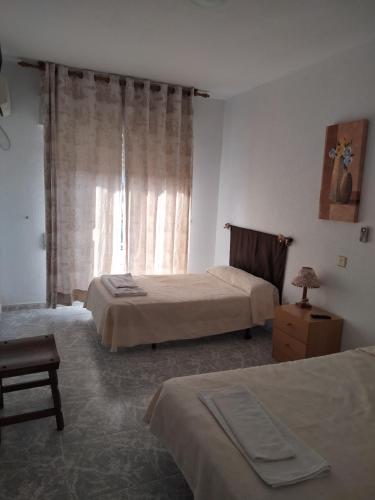 a hotel room with two beds and a window at Hostal Restaurante El Labrador in Talavera de la Reina