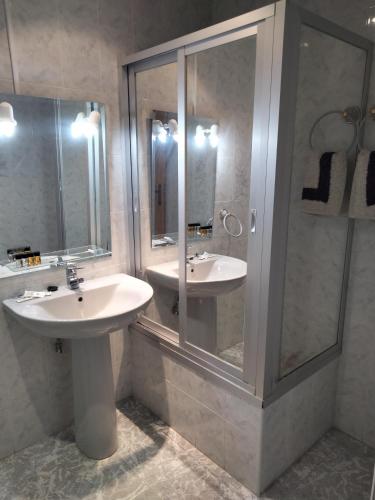 uma casa de banho com 2 lavatórios e uma cabina de duche em vidro. em Hostal Restaurante El Labrador em Talavera de la Reina