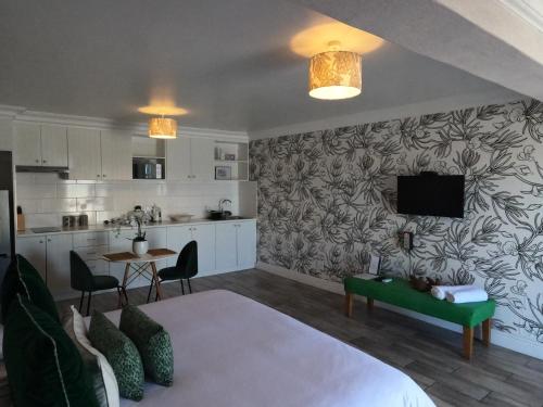 a living room with a bed and a kitchen at Thyme Wellness Spa and Guesthouse in Cape Town