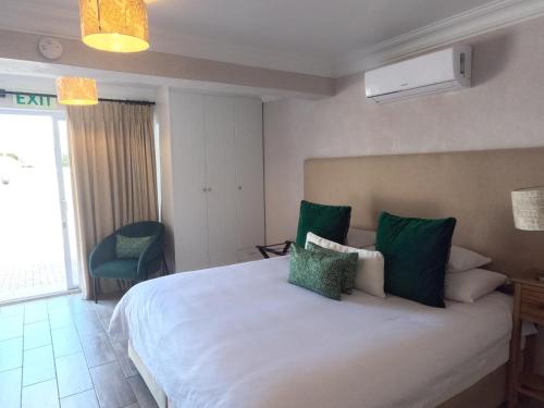 a bedroom with a large white bed with green pillows at Thyme Wellness Spa and Guesthouse in Cape Town