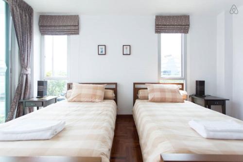 two beds in a room with two windows at P.K. Garden Home in Bangkok