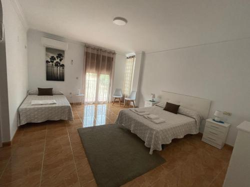 a bedroom with two beds and a table and chairs at ALOJAMIENTO Rural AVD SIERRA MÁGINA in Carchelejo