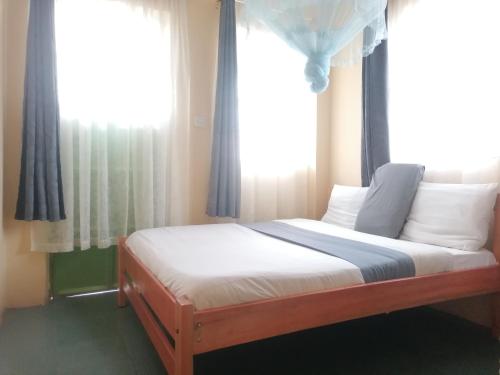 Bett in einem Schlafzimmer mit einem Fenster mit Vorhängen in der Unterkunft Forest green Inn in Kakamega