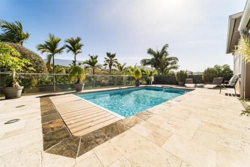une piscine dans une cour arrière avec des palmiers dans l'établissement Villa avec piscine vue mer et montagne, en pleine nature, à Saint-Joseph