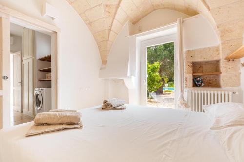 a white bedroom with a large bed and a window at Casale La Stella by Perle di Puglia in San Michele Salentino