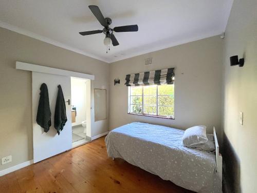 a bedroom with a bed and a ceiling fan at Rondebosch loft in Cape Town
