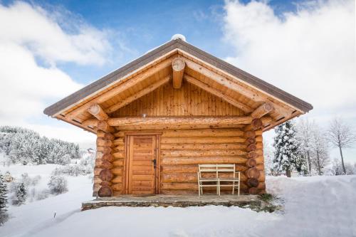 ein Blockhaus mit einer Holztür im Schnee in der Unterkunft Brunarica Macesen Smogavc in Zreče