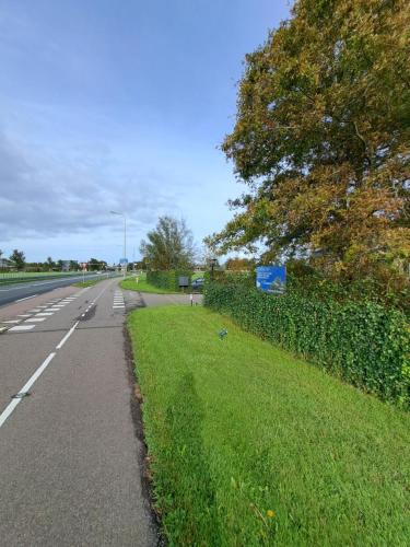 een lege weg met een heg naast een straat bij Carmen's Stay In - Jaagweg 13 Ilpendam in Ilpendam