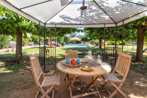 a table and chairs under an umbrella in a yard at Alghero prestigiosa antica dimora indipendente con piscina per 9 persone in Alghero