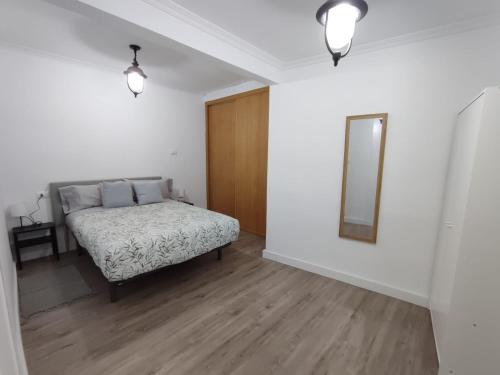 Schlafzimmer mit einem Bett und einem Wandspiegel in der Unterkunft Alójate en el corazón de Vigo in Vigo