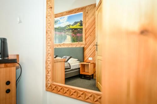 a mirror on a wall with a bed in a room at My Tatra Residence in Zakopane