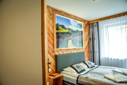 a bedroom with a bed with a painting on the wall at My Tatra Residence in Zakopane