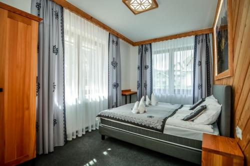 a bedroom with a bed in a room with windows at My Tatra Residence in Zakopane