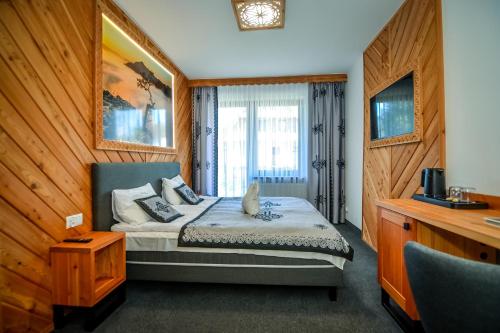 a bedroom with a bed and a television in a room at My Tatra Residence in Zakopane