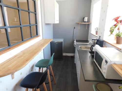 une petite cuisine avec un comptoir et deux tabourets dans l'établissement Les Brimbelles, Gîtes by Jul'Ine, à Brû