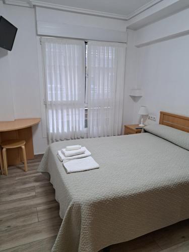 a bedroom with a bed with two towels on it at Pension Iruna in Santurce