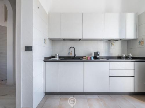 a white kitchen with white cabinets and a sink at Port View Apartment in Cagliari