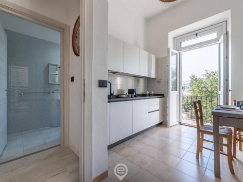 a kitchen with white cabinets and a table and a dining room at Port View Apartment in Cagliari