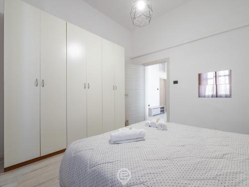 a white bedroom with a bed with white cabinets at Port View Apartment in Cagliari