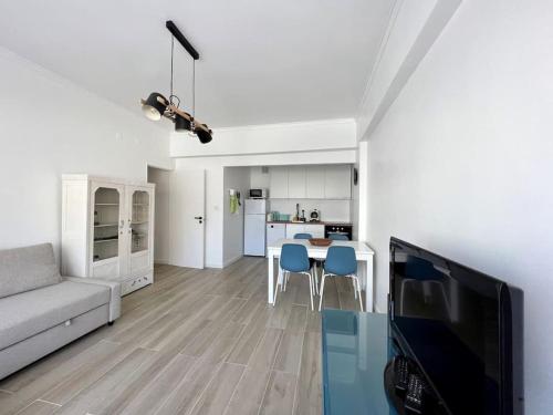 sala de estar con sofá y mesa con sillas azules en Apartamento muito central - 300 metros da Praia, en Costa da Caparica