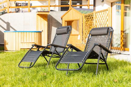 two lawn chairs sitting in the grass in front of a house at Pianeta Oro Chalet Allegra in Livigno