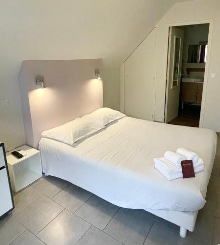 a bedroom with a large white bed with two towels at Hôtel Némo Aéroport de Pau - KB HOTEL GROUP in Sauvagnon