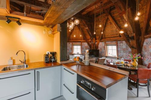 a kitchen with white cabinets and a wooden ceiling at De Molen van Egmond by Droomvilla in Egmond aan den Hoef