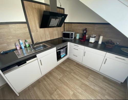 eine kleine Küche mit einer Spüle und einer Mikrowelle in der Unterkunft Ferienwohnung Am Rathausberg in Schiffweiler