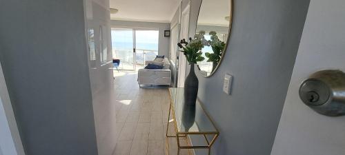 a hallway with a mirror and a vase on the wall at 201 Coral Island, 88 Coral Road, Bloubergstrand in Bloubergstrand