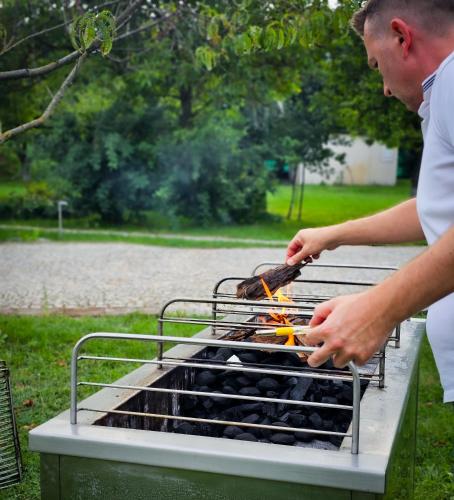 a man is cooking food on a grill at Gościniec Gryszczeniówka & SPA in Wargowo