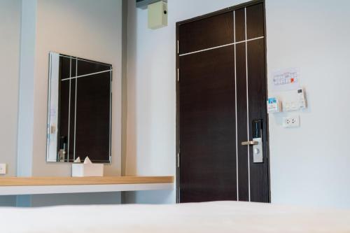 a wooden door in a room with a mirror at Goodday Hotel in Ban Nong Waeng