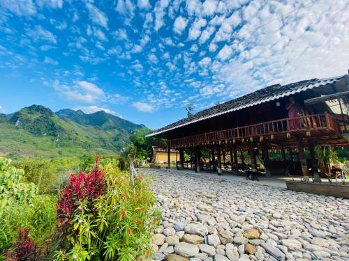 a building with a stone road next to a mountain at Tày Cốc Pảng Homestay in Làng Cac
