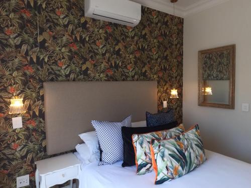 a bedroom with a bed and a wall with floral wallpaper at Thyme Wellness Spa and Guesthouse in Cape Town