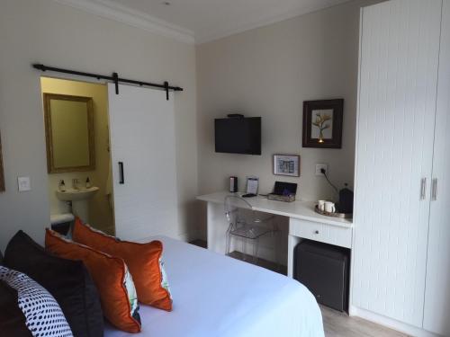 a bedroom with a white bed and a desk at Thyme Wellness Spa and Guesthouse in Cape Town