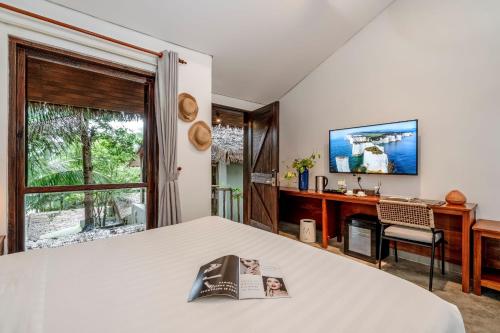 a bedroom with a bed and a desk and a window at M Village Phu Quoc in Phu Quoc