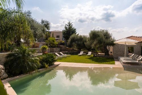 a swimming pool in a yard with chairs and an umbrella at Villa Resperi in Gonia