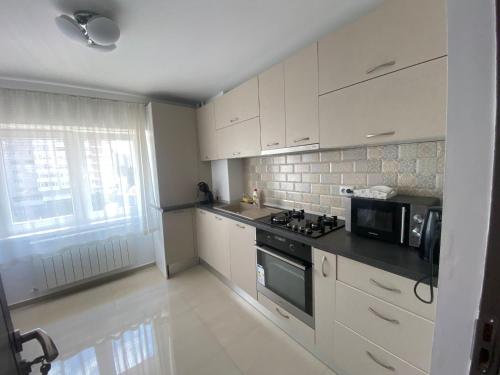 a kitchen with white cabinets and a stove and microwave at Apartament Central Suceava in Suceava