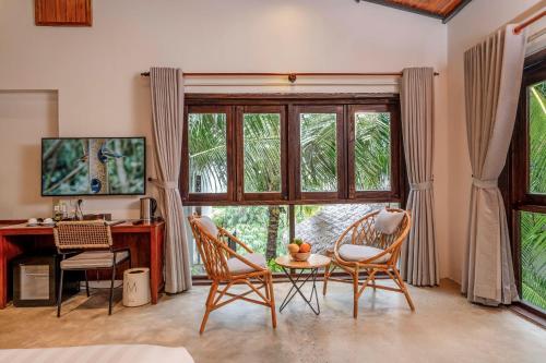 a living room with a table and chairs and a large window at M Village Phu Quoc in Phu Quoc