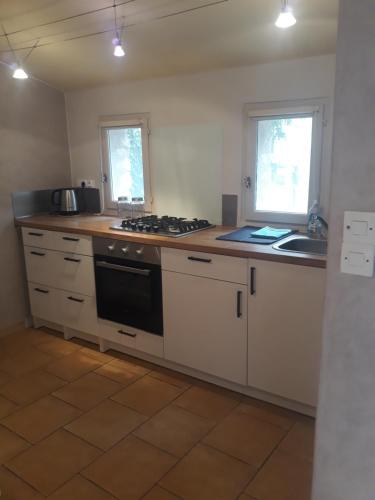 uma cozinha com armários brancos e um forno com placa de fogão em La maison du jardin em Rustrel