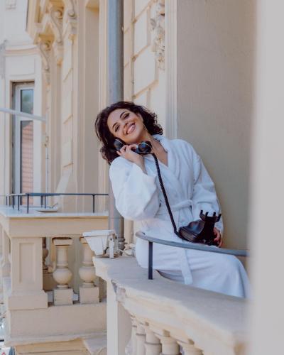 a woman sitting on a ledge talking on the phone at Hotel Le Grimaldi by Happyculture in Nice