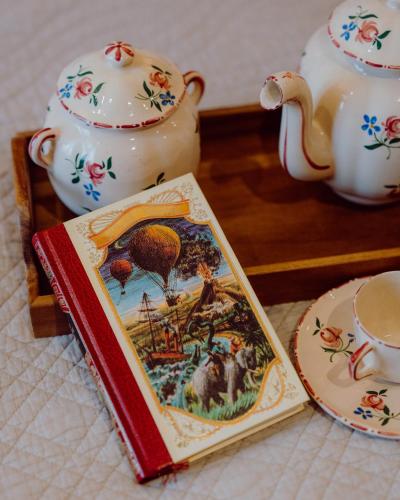 a book next to a tea pot and a tea cup at Hotel Le Grimaldi by Happyculture in Nice