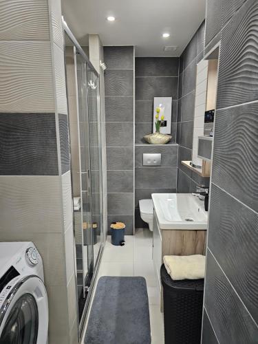 a bathroom with a sink and a washing machine at Apartment SAND - Entry with PIN 0 - 24h, Luxury massage chair,Infrared sauna,FREE CANCELLATION 24 hours before Check In, Premium pillows and mattress in Slavonski Brod
