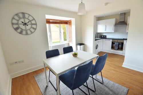 comedor con mesa, sillas y reloj en Luxury 2 BR Fully Furnished Flat in Crawley - 2 FREE Parking Spaces en Crawley