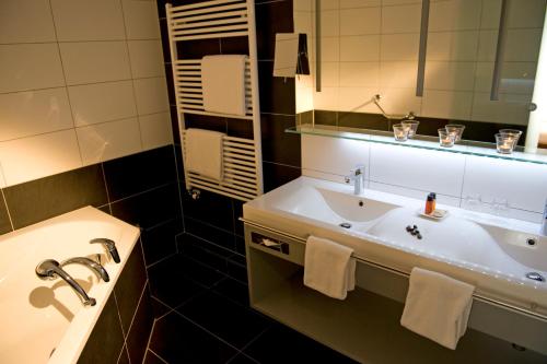 a bathroom with a sink and a large mirror at Quellenhof UNIQUE in Leukerbad